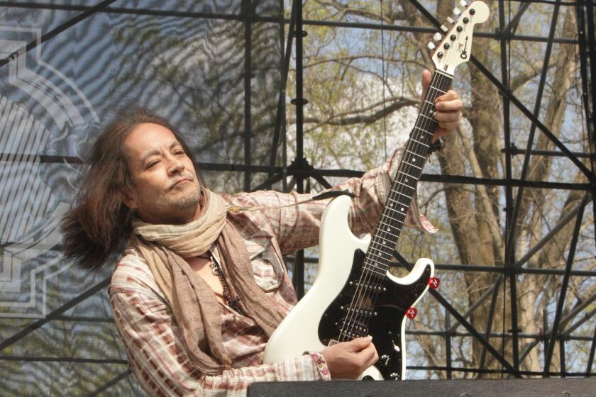 Guitarist Jake E. Lee lifts his guitar while playing onstage