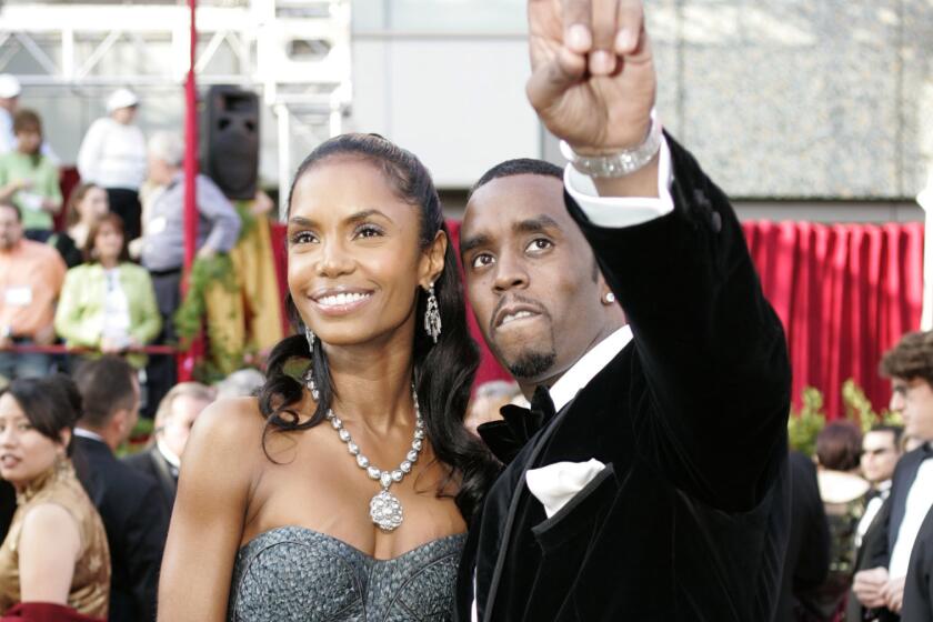 Kim Porter wears a gown as she poses next to Sean 'Diddy' Combs on a red carpet