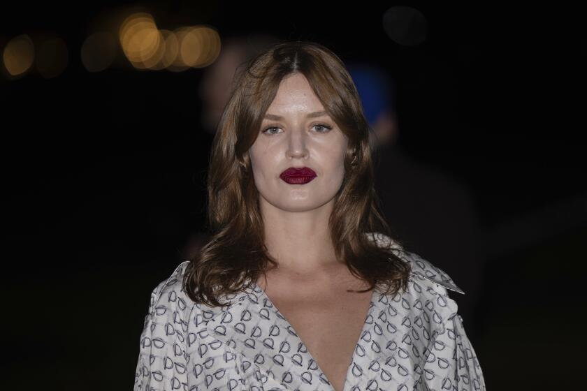 Georgia May Jagger poses in a white printed dress and dark red lipstick at the Burberry Winter 2024 fashion show in London