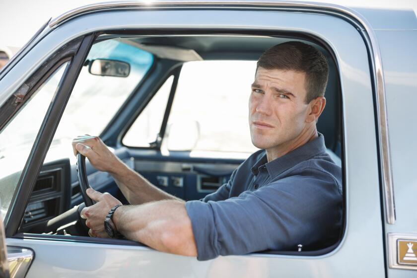 A young man looks at the camera from a truck window