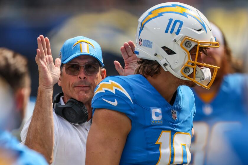 Chargers coach Jim Harbaugh slaps quarterback Justin Herbert on the back before a game.