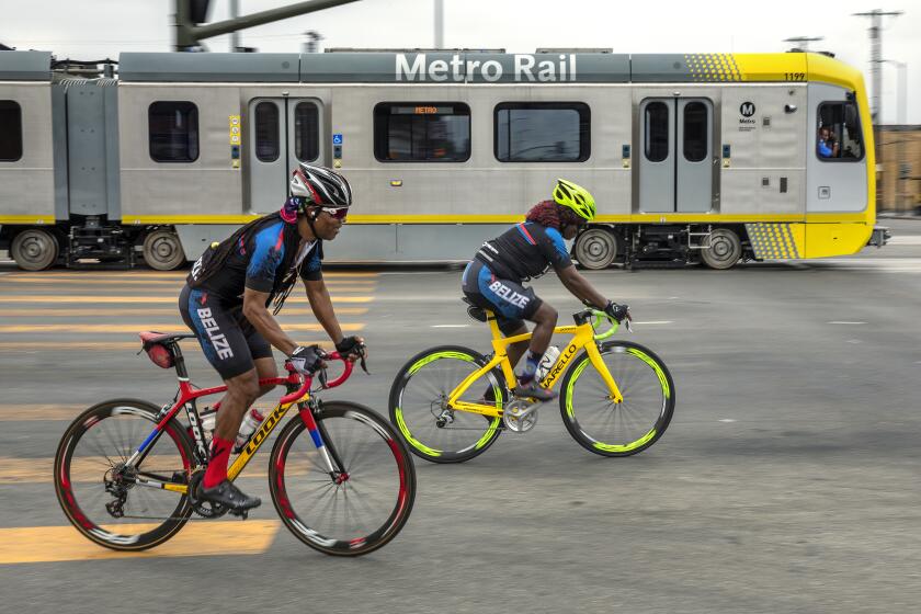 LOS ANGELES, CA -AUGUST 22, 2022:Bicycle riders pedal along Crenshaw Blvd. near Slauson Ave. in Los Angeles as a Metro train, that is part of the new K line passes by during a test run. Metro's K Line (Crenshaw/LAX Transit Project) will extend light rail from the existing Metro E Line (Expo) at Crenshaw and Exposition Boulevards to the Metro C Line. While the rail line includes 8 new stations, only 7 will be open in the fall of 2022. The train will travel 8.5 miles and will serve the cities of Los Angeles, Inglewood, and El Segundo and portions of unincorporated Los Angeles County. (Mel Melcon / Los Angeles Times)