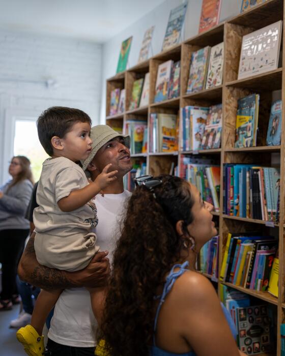 Zaden Alvarez, 2, and his parents Eric Alvarez and Sandy Andrade look for a book to read from LA libreria's bookcase 