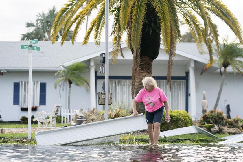 OSPREY, FLORIDA - OCTOBER 10: A woman moves storm debris on a flooded street in the aftermath of Hurricane Milton on October 10, 2024 in Osprey, Florida. The hurricane made landfall as a Category 3 hurricane in the Siesta Key area. (Photo by Sean Rayford/Getty Images)