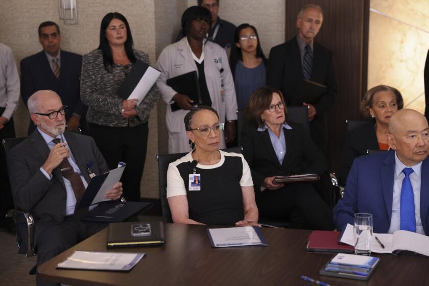 A group of hospital executives and aides at a hearing.