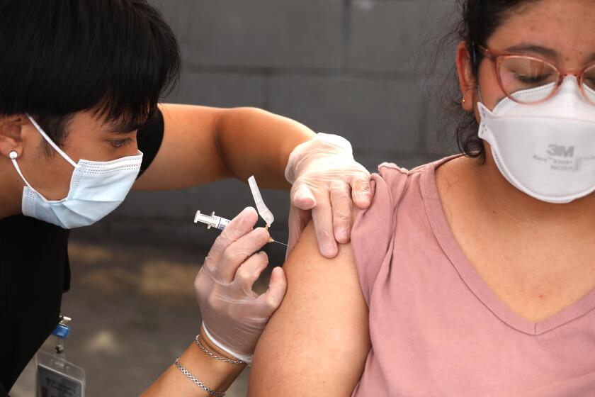 LYNNWOOD, CA - SEPTEMBER 22, 2023 - USC graduate and pharmacy student Jordan Gelacio gives Aura Viva a free flu shot at a vaccine clinic provided by the L.A. Care and Blue Shield of California Promise Health Plans at the Community Resource Center in Lynnwood on September 22, 2023. According to Hector Andrade, with L.A. Care and Blue Shield of California, they were not able to get COVID-19 vaccines for this clinic. They hope to have some by next week for other clinics. They are hosting10 walk-in vaccine clinics at their jointly operated Community Resource Centers across Los Angeles County, providing members and the public with no-cost flu and upcoming COVID-19* vaccines. Visitors also had their blood pressure checked and blood sugar measured. The vaccine clinics will take place from September 22 to October 20, 2023. (Genaro Molina / Los Angeles Times)