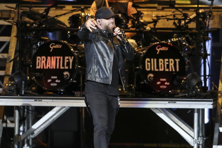 Brantley Gilbert points while perfoming onstage in all black clothes