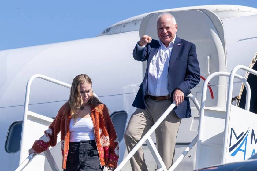 Democratic vice presidential candidate Tim Walz, governor of Minnesota, points to local dignitaries as he departs a plane at Sacramento International Airport with daughter Hope Walz on Tuesday. Walz is visiting the city on a fundraising trip.