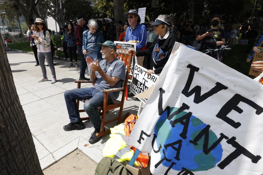 LOS ANGELES-CA-APRIL 19: Senior activist David Rosenstein, with Their Act, seated in a rocking chair attends a climate rally and march with Ann Bartz (2ndL) Jeff Olmstead (C) and Monica Sena at Los Angeles City Hall on Friday April 19, 2024, in Los Angeles, California. (Kevork Djansezian/For The Times)