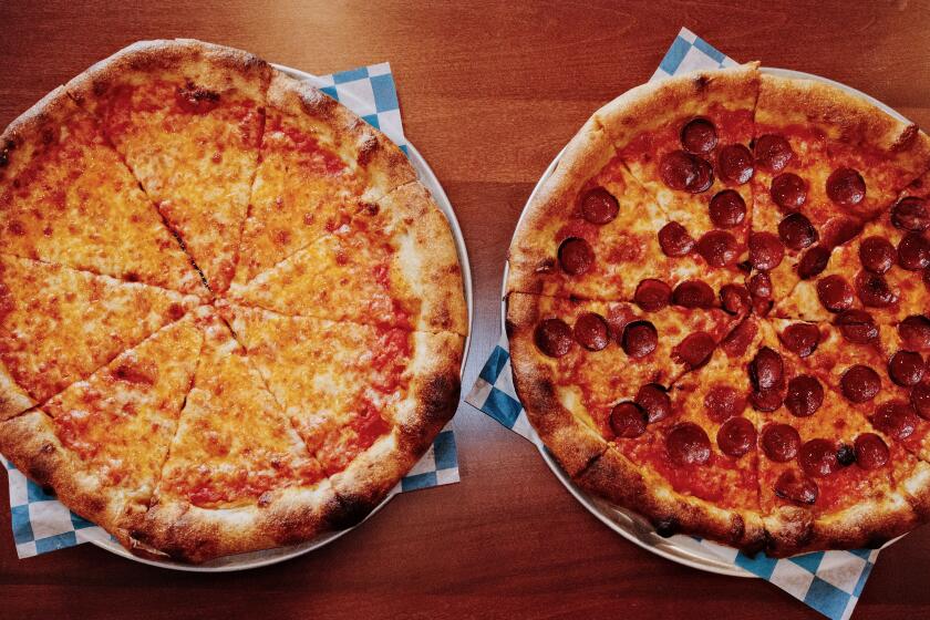 An overhead of whole cheese and pepperoni pizzas on blue-and-white checkered paper at LaSorted's pizzeria in Chinatown