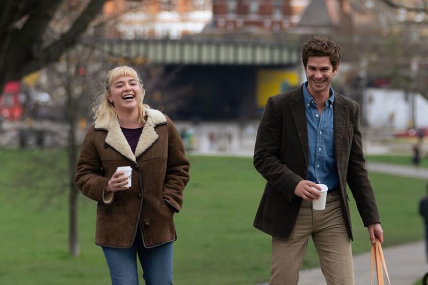 Two people walk in a park, smiling.